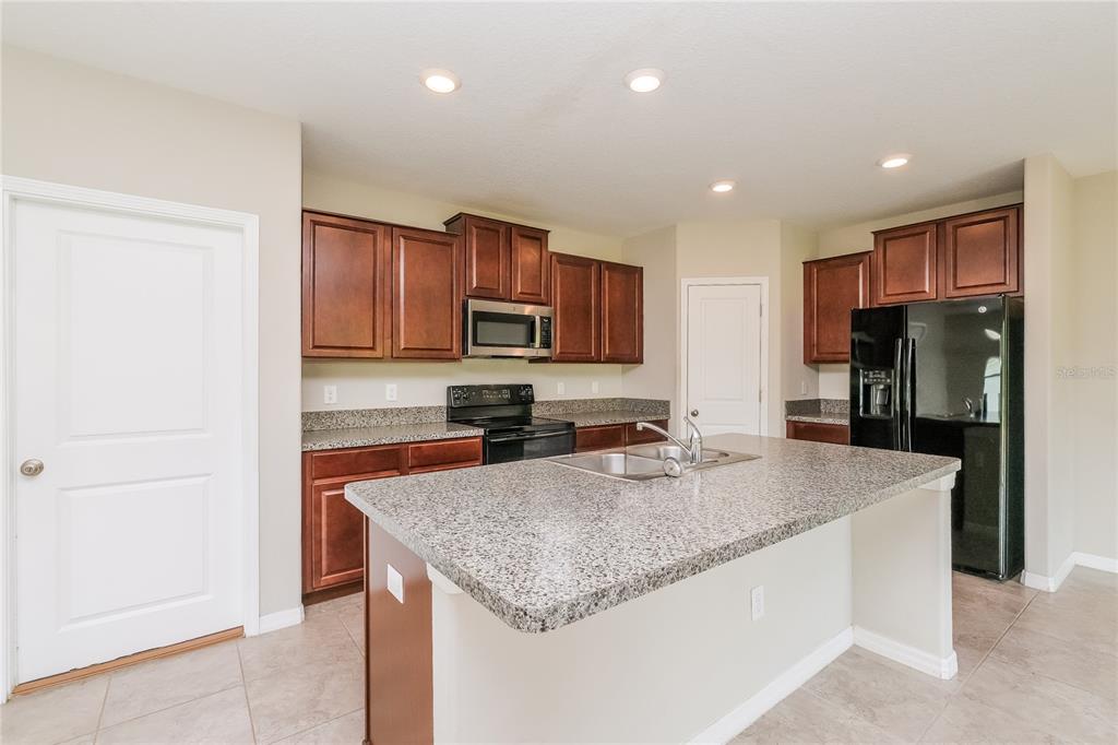 36125 Stable Wilk Avenue Zephyrhills, FL 33541 - Photo 5 of 17 a kitchen with granite countertop a refrigerator and a sink