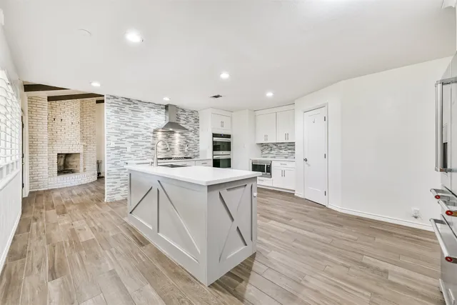 a kitchen with kitchen island wooden floors appliances and center island