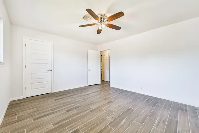 an empty room with wooden floor and ceiling fan