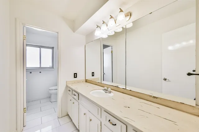 a spacious bathroom with a granite countertop sink a toilet and a mirror