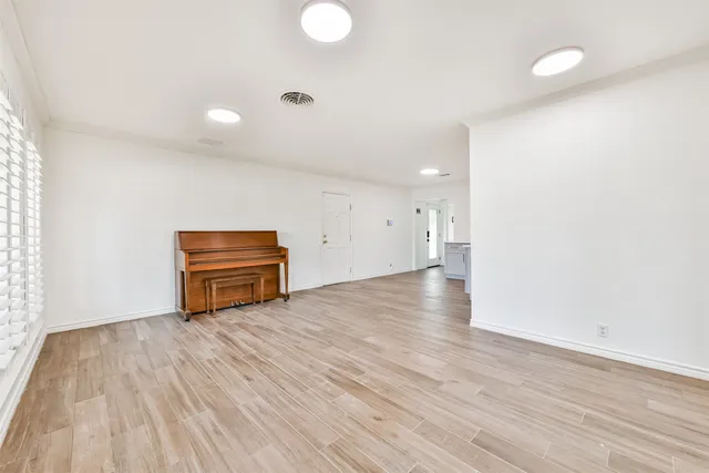 a view of kitchen and empty room with wooden floor