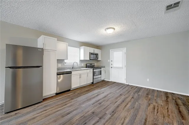 a kitchen with white cabinets stainless steel appliances and a refrigerator