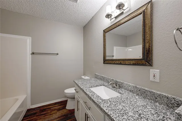 a bathroom with a granite countertop sink a toilet and a mirror