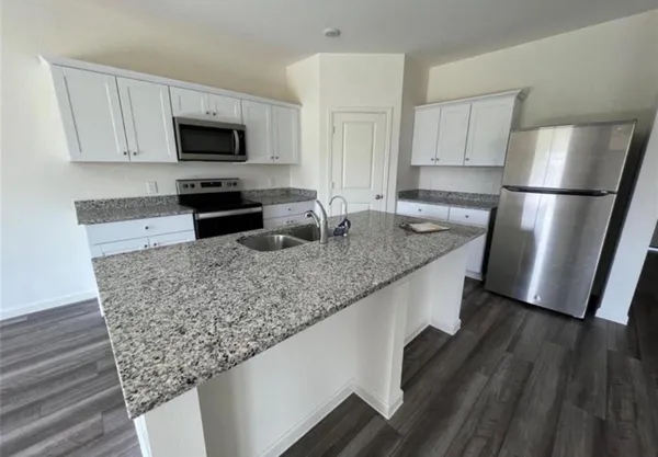 a kitchen with stainless steel appliances granite countertop a sink stove microwave and refrigerator