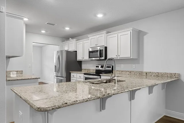 a kitchen with granite countertop white cabinets and stainless steel appliances