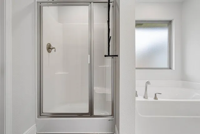 a view of an empty room with kitchen and window