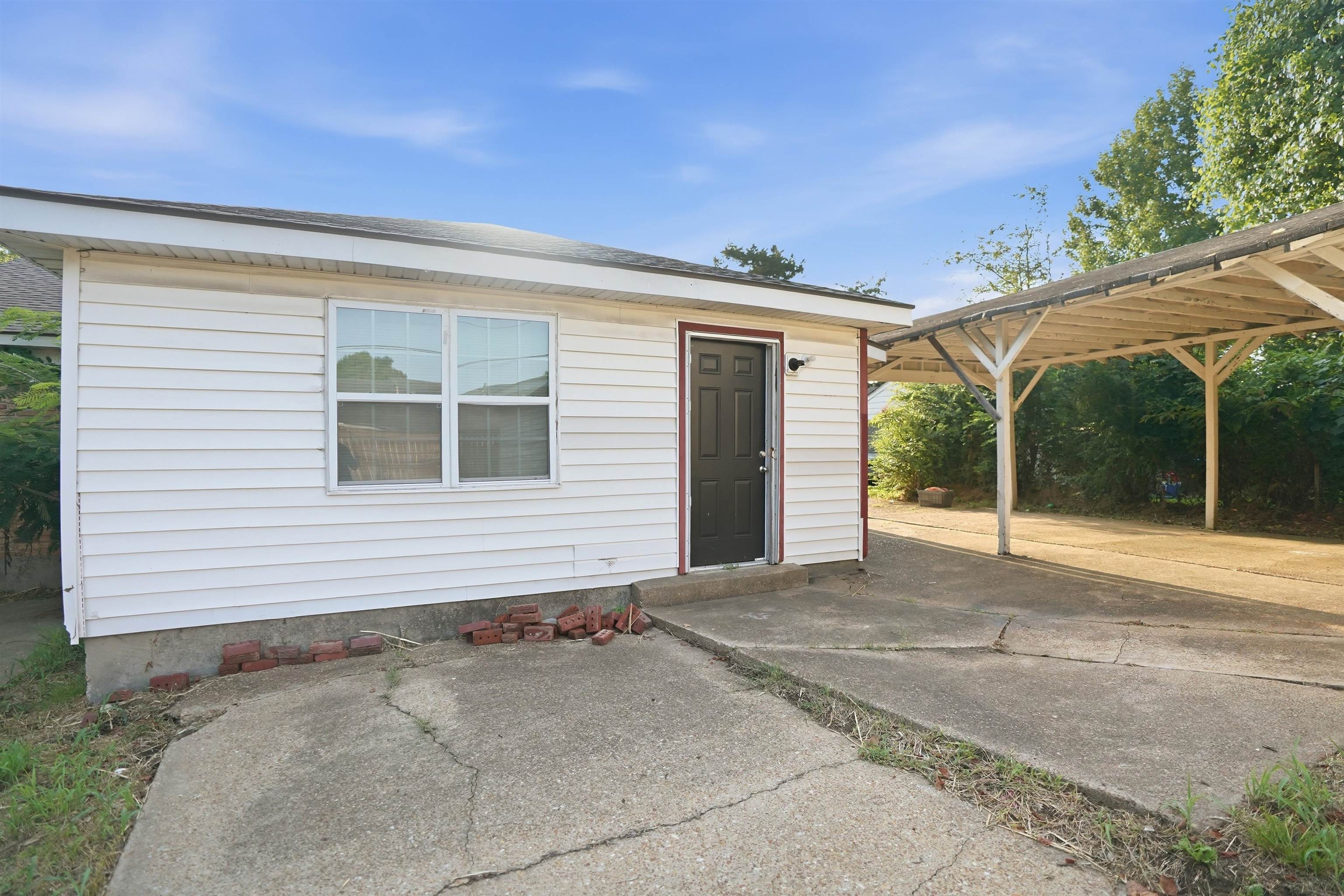 3736 Range Line Road Memphis, TN 38127 - Photo 17 of 18 White horizontal siding exterior with a dark entry door and an attached carport
