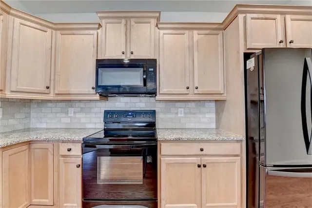 a kitchen with stainless steel appliances granite countertop wooden cabinets granite counter tops and a hard wood floors