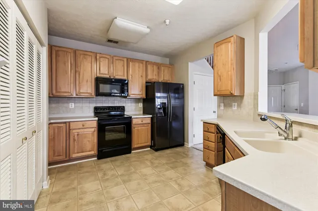 a kitchen with stainless steel appliances granite countertop a stove top oven a sink dishwasher a refrigerator and a microwave oven