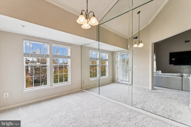 a view of an empty room with a window and a kitchen
