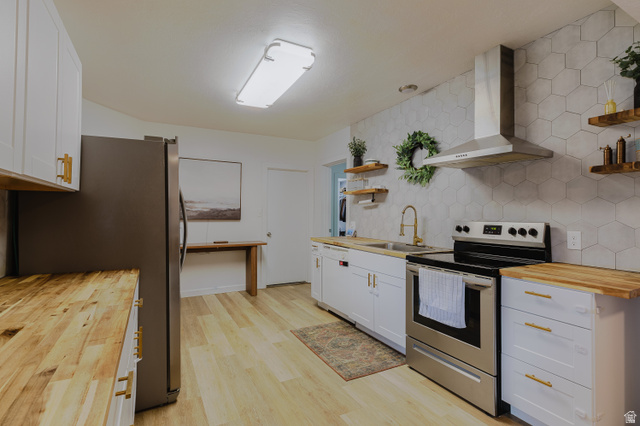 244 North 600 West Logan, UT 84321 - Photo 25 of 30 Contemporary kitchen featuring light wood-finish flooring, white cabinetry with gold-tone hardware, butcher block countertops, a stainless steel range, and a hexagonal tile backsplash