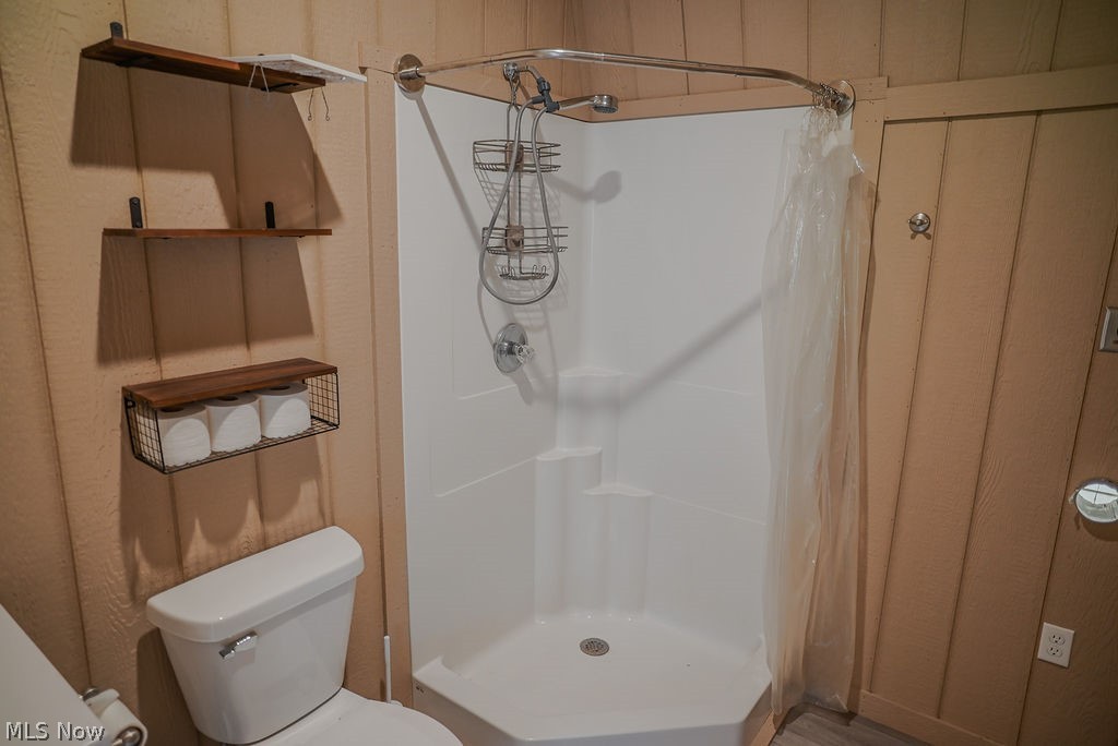 1547 Providence Road Elizabeth, WV 26143 - Photo 12 of 32 Compact bathroom featuring a corner shower stall, white toilet, and vertical wood-plank wall paneling