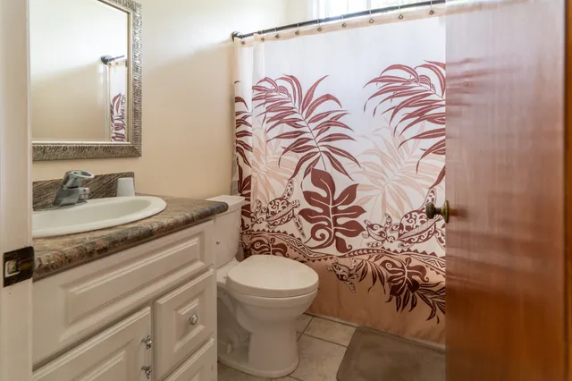 a bathroom with a granite countertop sink and a toilet