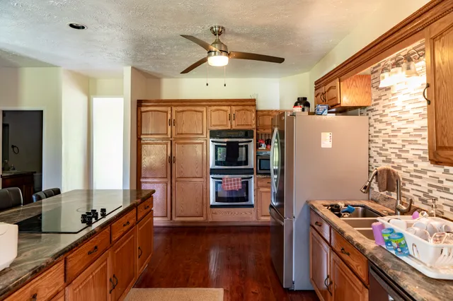 a kitchen with stainless steel appliances a stove top oven a refrigerator a sink and dishwasher with wooden floor