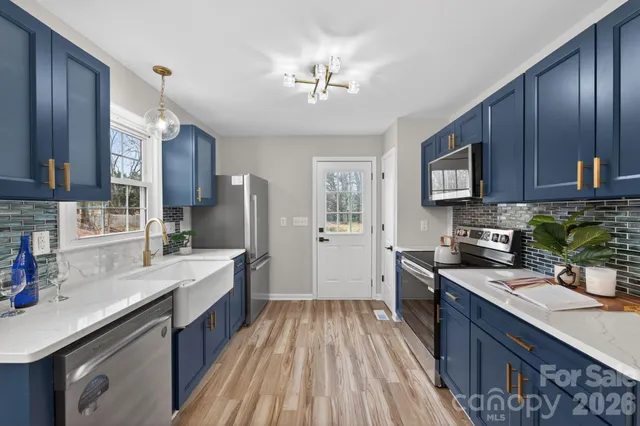 a open kitchen with stainless steel appliances granite countertop a refrigerator a sink dishwasher a stove and a dining table with wooden floor