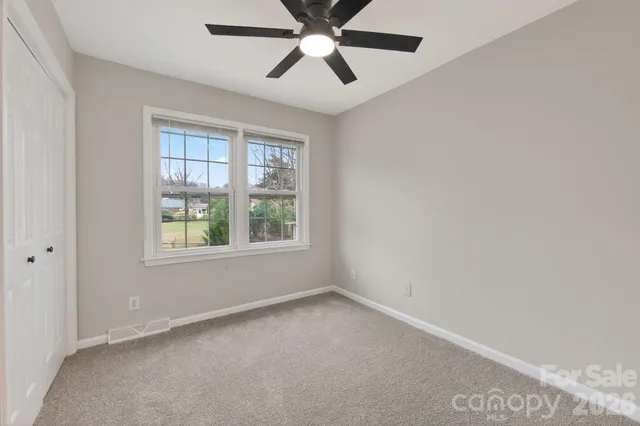 an empty room with windows and fan