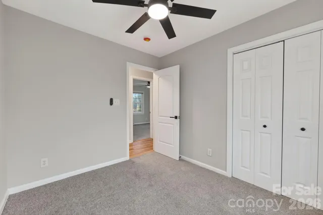 a view of an empty room and chandelier fan