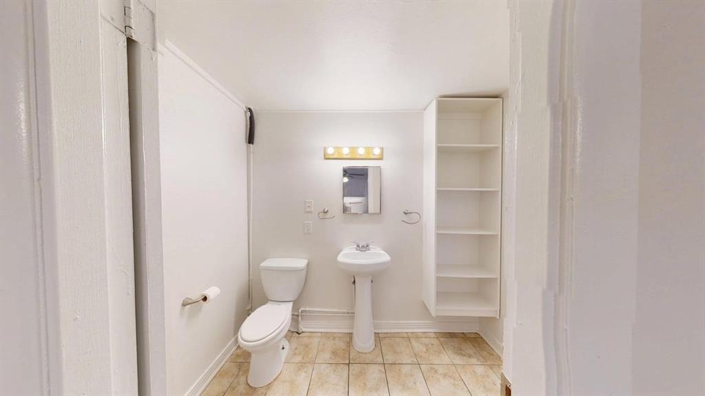 2246 Anson Road Dallas, TX 75235 - Photo 16 of 20 Bathroom featuring a pedestal sink, toilet, built-in open shelving, vanity lighting, and tile flooring