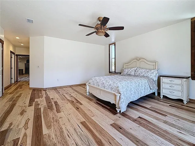 an empty room with wooden floor fan and windows