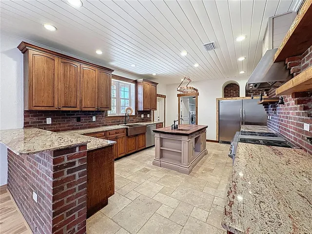 a large kitchen with stainless steel appliances granite countertop a stove and cabinets