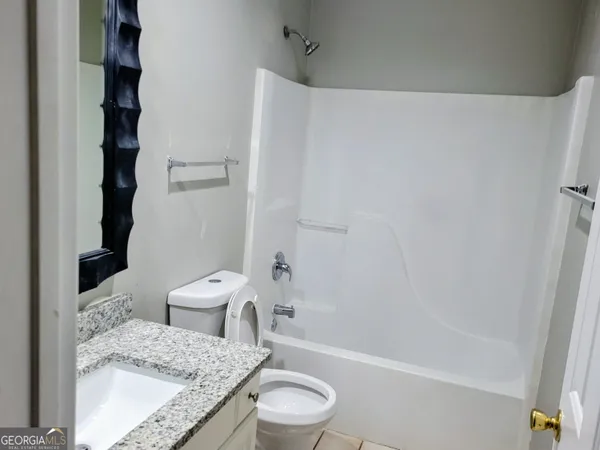 a bathroom with a granite countertop sink toilet a mirror and shower
