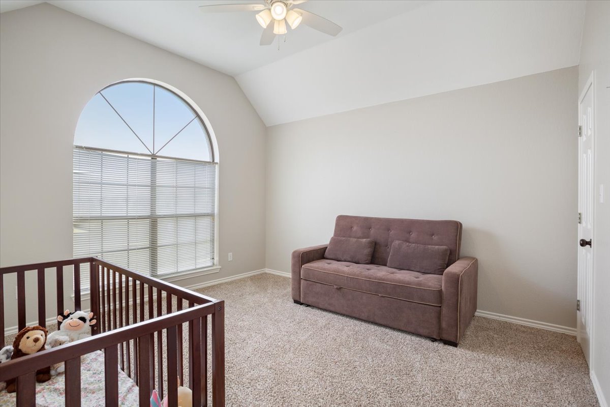 8600 Five Wells Road Rogers, TX 76569 - Photo 22 of 40 Carpeted bedroom with a nursery area, vaulted ceiling, and a ceiling fan