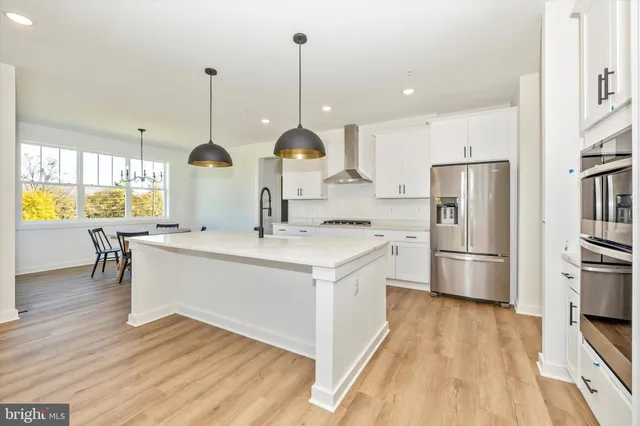 a kitchen with stainless steel appliances a stove a sink a center island and wooden floor