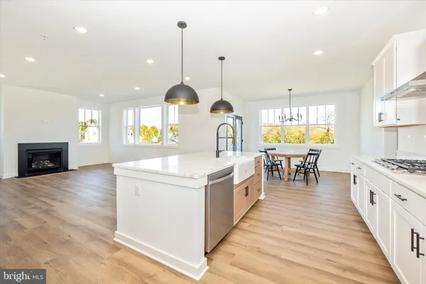 a kitchen with stainless steel appliances granite countertop a stove top oven a sink a dining table and chairs with wooden floor