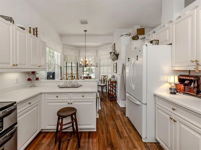 a kitchen with stainless steel appliances white cabinets and wooden floor