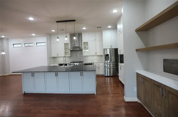 a large kitchen with stainless steel appliances a large counter top a stove a refrigerator and a sink