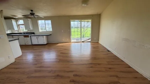 a view of an empty room with a window and wooden floor