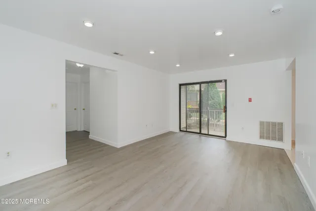 a view of an empty room with wooden floor and closet