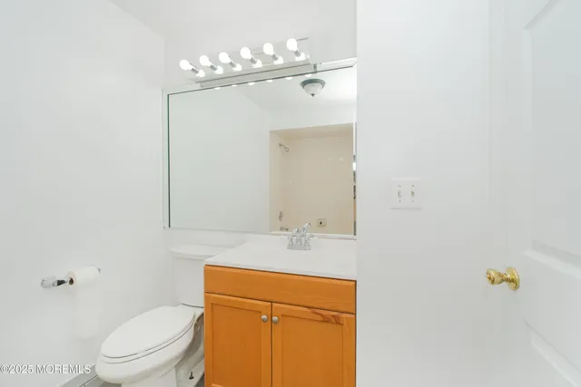 a bathroom with a granite countertop sink toilet and mirror