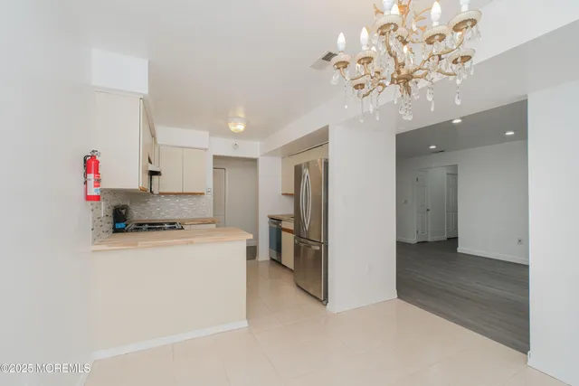 a kitchen that has a lot of white cabinets and stainless steel appliances