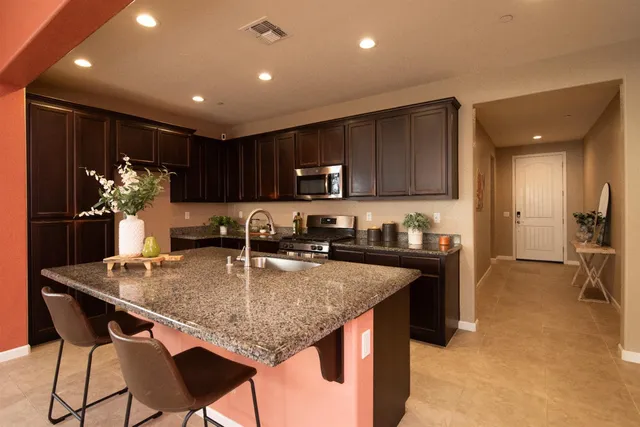 a kitchen with kitchen island granite countertop a sink and cabinets