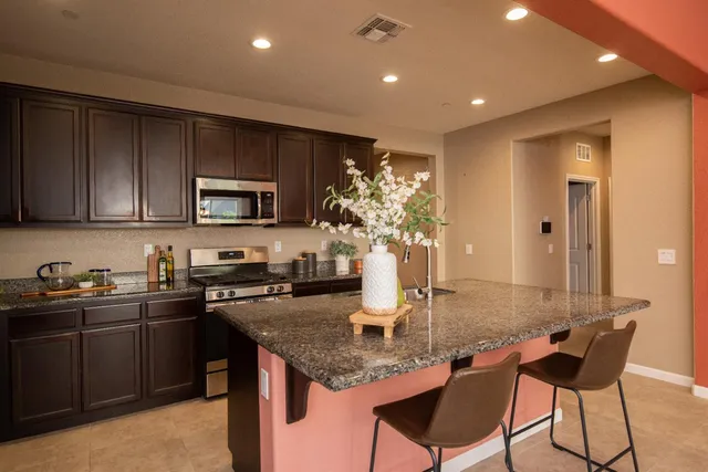 a kitchen with granite countertop stainless steel appliances a stove sink and cabinets