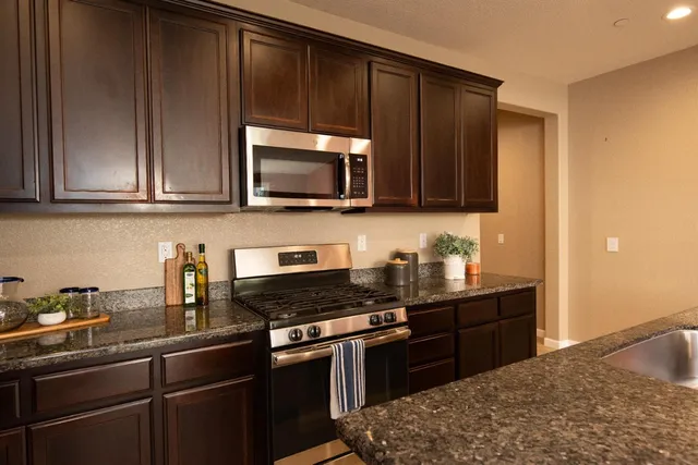 a kitchen with granite countertop a stove a sink dishwasher and cabinets with wooden floor