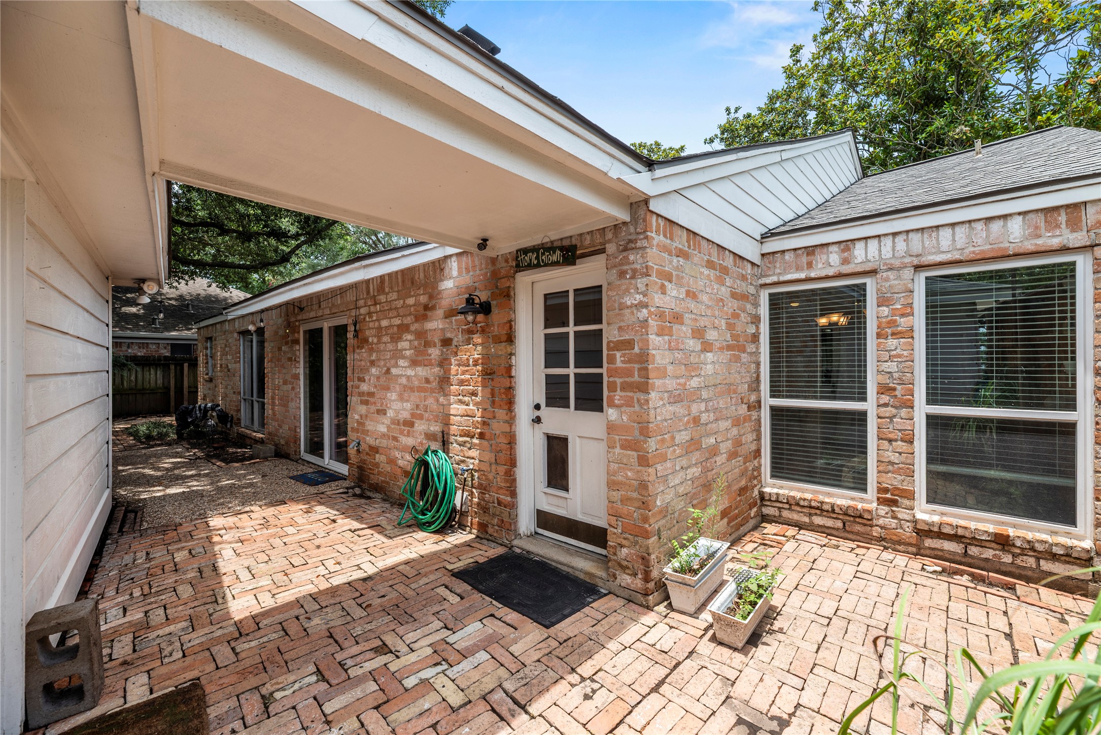 14203 Wickersham Lane Houston, TX 77077 - Photo 23 of 25 Charming brick-paved breezeway patio nestled between the home and garage, featuring multiple glass doors for easy indoor-outdoor flow and high-exposure windows.
