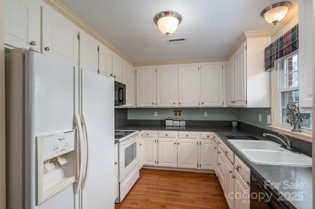 a kitchen with granite countertop a sink a counter top space stainless steel appliances and cabinets