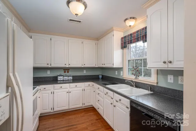 a kitchen with granite countertop a sink a stove and cabinets
