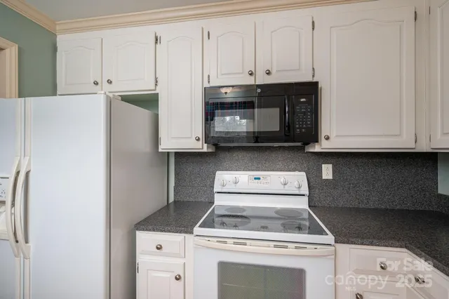 a kitchen with granite countertop a stove and a microwave
