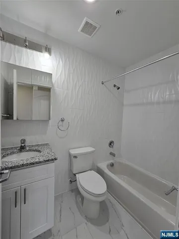 a bathroom with a granite countertop toilet a sink and bathtub