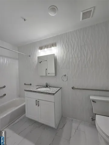 a bathroom with a granite countertop sink a toilet and bathtub