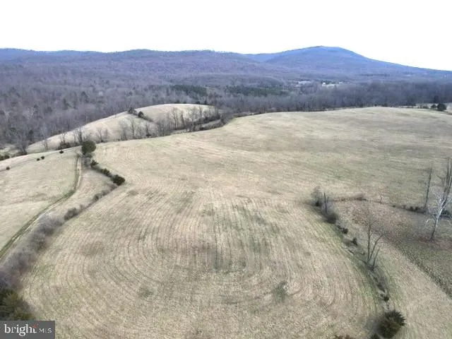 a view of a dry field with mountains in the background
