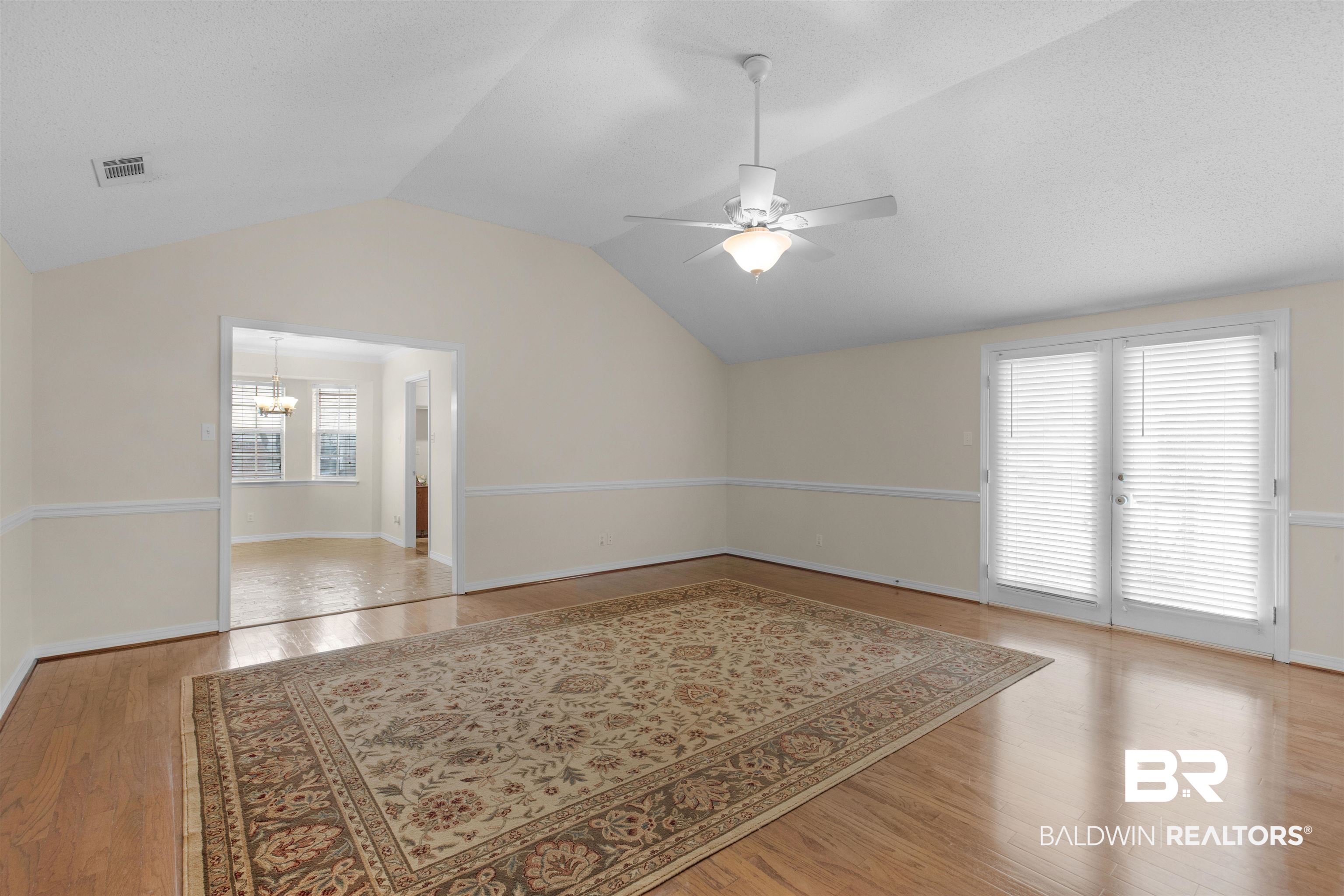 7225 Smithfield Road East Mobile, AL 36695 - Photo 9 of 27 Spare room featuring visible vents, baseboards, vaulted ceiling, light wood-style flooring, and ceiling fan with notable chandelier
