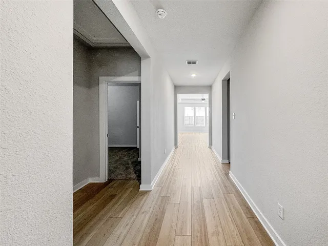 a view of a hallway with wooden floor and a bathroom