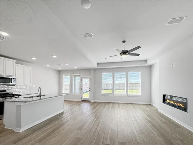 a view of an empty room with window and wooden floor