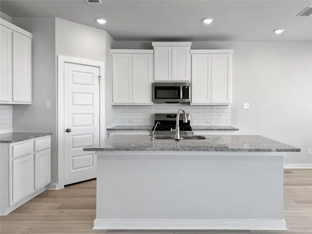 a kitchen with stainless steel appliances granite countertop a sink a stove and a refrigerator