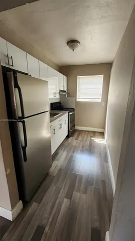 a kitchen with granite countertop a refrigerator and wooden floor