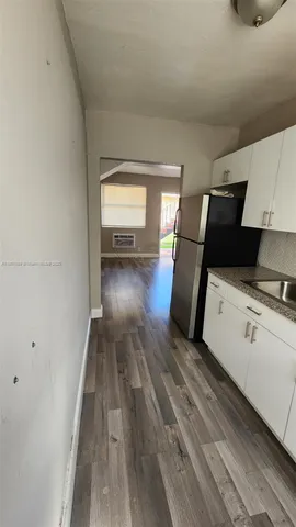 a view of a kitchen with wooden floor and electronic appliances
